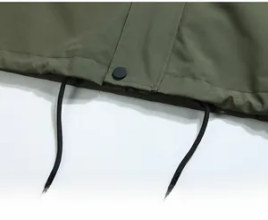 Detail view of military green jacket hem with black adjustable drawstrings and snap buttons