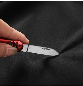 Detail showing high-strength scratch-resistant black fabric tested with a metal blade
