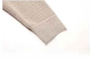 Détail des poignets côtelés du pull en chenille beige avec motif de tricot géométrique