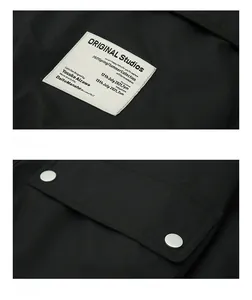 Detail of a black workwear jacket showing windproof fabric and metallic pocket snaps