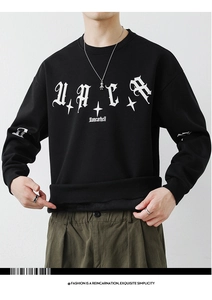 Detail of black crewneck sweatshirt featuring white Gothic lettering and cross star prints