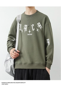 Detailed view of army green crewneck sweatshirt with white gothic letter prints and stars