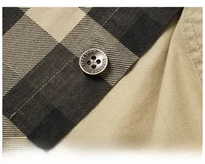 Detailed macro view of bronze button with FREE SPIRIT text on plaid cotton shirt