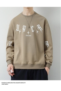 Detailed view of khaki sweatshirt with white gothic lettering and cross star graphics