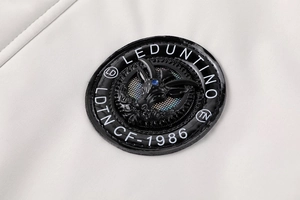Detail van een zwarte lederen badge met dierenreliëf op een beige winterjas van katoen