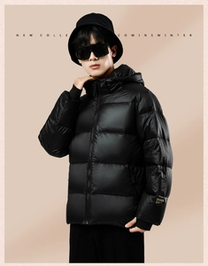 Close-up of black hooded down jacket featuring quilted panels and ribbed cuffs for winter