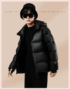 Detail of black glossy puffer jacket sleeve with yellow branded cuff tag for men