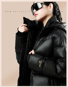 Detail of black glossy puffer jacket with golden embroidered label on the cuff