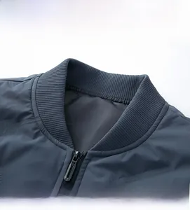 Detail view of the rib-knit stand collar and metal zipper on this blue down jacket for men