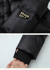 Detail of black down vest featuring gold embroidery patch and ribbed thumbhole cuffs