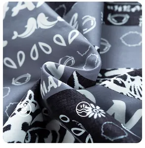 Close-up of printed woven fabric showing MAX lettering and floral patterns on gray-blue base