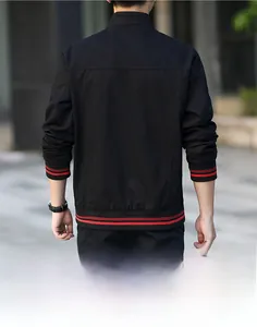 Détail de la veste en coton noir avec poignets côtelés à rayures rouges et couture au dos