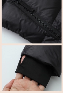 Detail of waterproof zipper and windproof cuffs with thumb holes on black puffer jacket