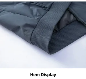 Detailed close-up of quilted down jacket hem showing ribbed cuff and metallic zipper