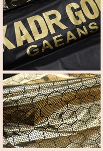 Detail of matte black fabric with gold lettering and metallic honeycomb texture