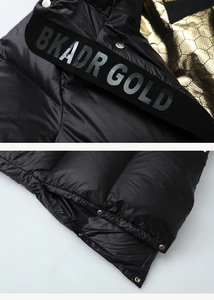 Detail of black down jacket with golden honeycomb lining and metallic snaps