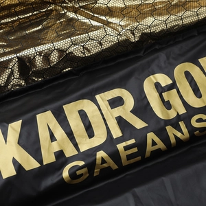 Close-up of black and gold puffer vest featuring honeycomb texture and KADR GO metallic print