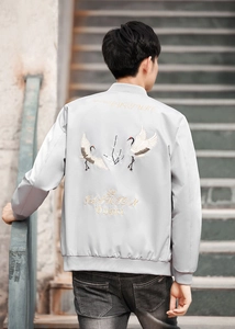 Close-up of crane and floral embroidery on back of light grey men's bomber jacket