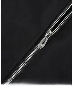 Close-up of smooth metal zipper detail on black jacket with embossed puller tab