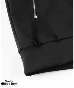 Detail of men's black jacket featuring metal zipper pocket and elastic ribbed hemline