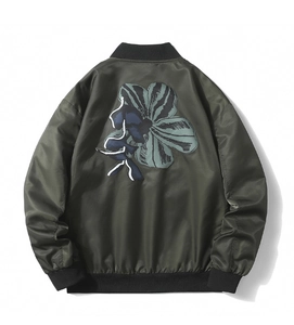 Detail view of the large abstract flower print on the back of a dark green bomber jacket