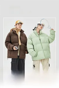 Dettaglio di piumini invernali oversize in marrone e verde con collo alto e vestibilità ampia