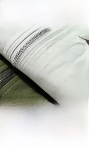 Detailed macro view of olive green and white fabric with a premium metal zipper on the jacket