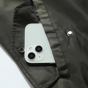 Men's olive varsity bomber jacket featuring a deep functional pocket with metal snap button