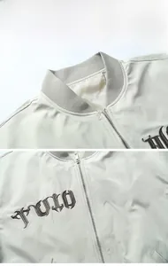 Detailed view of TULO WERK embroidery and ribbed collar on a beige baseball jacket