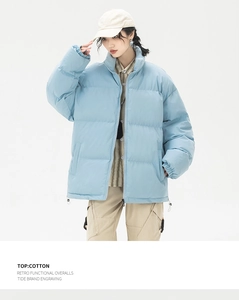 Dettaglio del piumino azzurro con stile retrò funzionale e silhouette oversize trendy