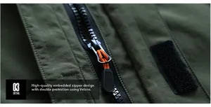 Détail d'une veste d'extérieur vert armée avec fermeture éclair et cordon orange