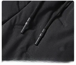 Détail du cordon de serrage noir avec embout en plastique sur le pantalon d'hiver