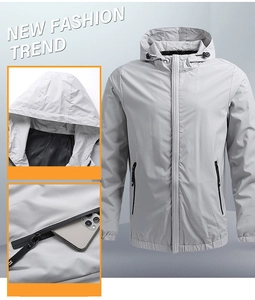 Detail view of light grey hooded windbreaker showing functional zipper pockets for phone