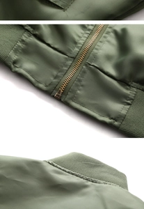 Detail of military green bomber jacket showing copper zipper, ribbed hem, and stitching