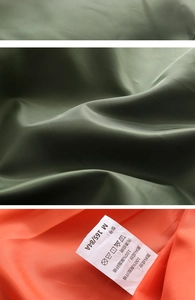 Detail view of olive green polyester fabric with bright orange lining and care label