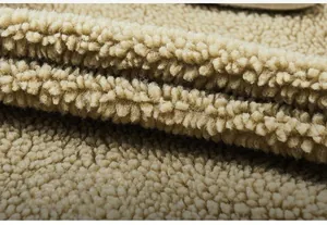 Close-up of soft beige sherpa fleece lining showing thick curly fiber texture on a jacket