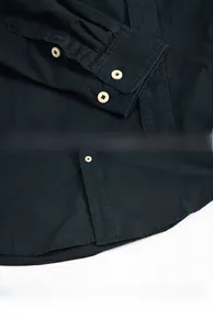 Detailed view of the dark navy cotton shirt with quality buttons and arc hem design