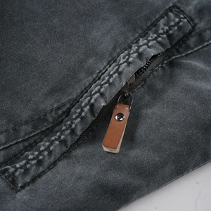 Detail of washed cotton jacket featuring a metal zipper and brown leather puller