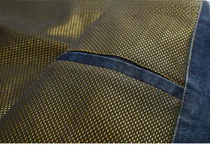 Detailed close-up of dark blue denim cuff featuring gold honeycomb mesh lining and stitching