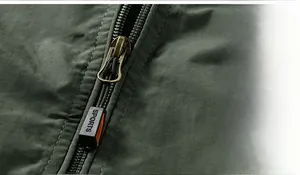 Close-up of olive green jacket zipper with SPORTS tag and textured polyester fabric