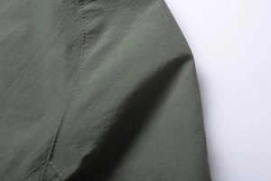 Close-up of olive green military jacket shoulder with double-stitched reinforced seams