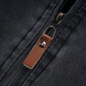 Close-up of durable cotton jacket featuring metal zipper and brown leather pull tab