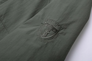 Detailed view of high-quality outdoor embroidery on olive green washed cotton jacket