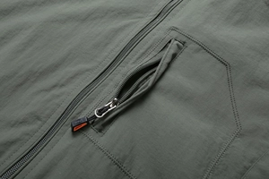Detailed macro view of olive green jacket chest pocket with zipper and sports puller