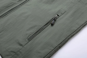 Detail of army green outdoor jacket featuring sports zipper pull and windproof fabric