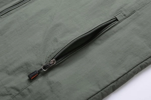 Detailed macro view of olive green jacket side pocket with sports zipper puller