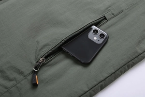 Detail of army green outdoor jacket with durable twill fabric and large zipper pocket