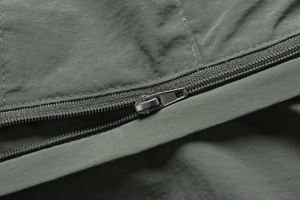 Macro shot of durable matte metal zipper and olive green twill fabric on a jacket