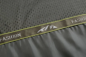 Detail of olive green jacket featuring breathable mesh fabric and fashion logo ribbon
