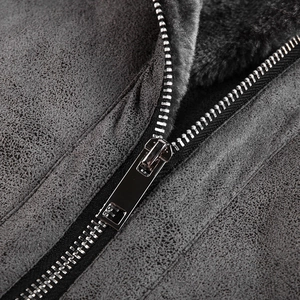 Detail of silver metal zipper and thick black faux fur lining on a grey suede jacket